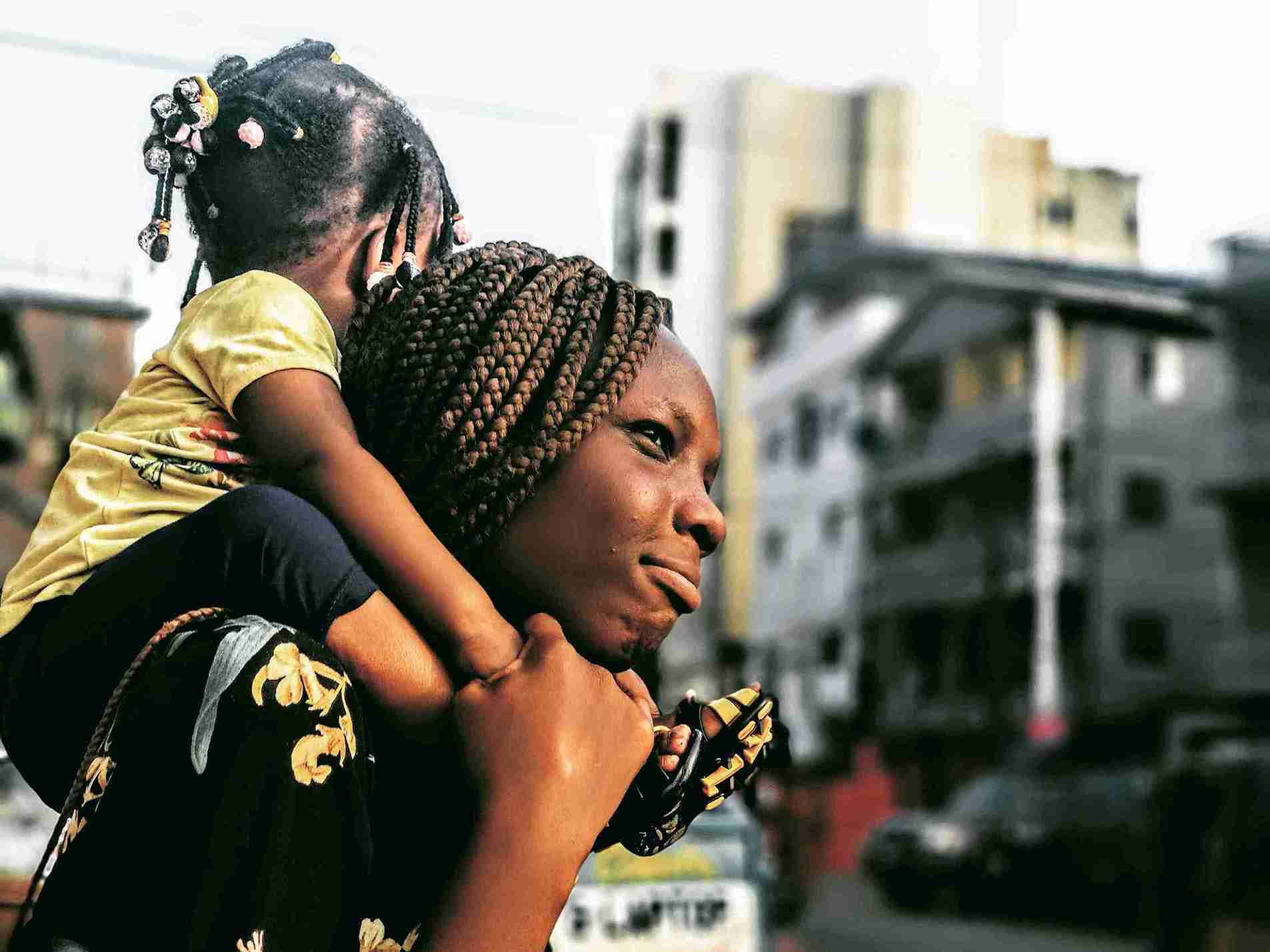 A young single mother holds her child close, capturing the strength and quiet determination of millions of women raising families alone while striving for financial independence.